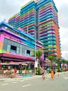a large colorful building with people walking in front of it at Phòng Studio, Tòa Ibiza, Flamingo Hải Tiến in Nam Khê