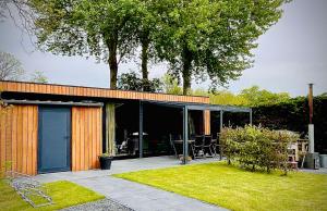 a house with an enclosed patio with a table and chairs at It Fugelnest in Tzummarum