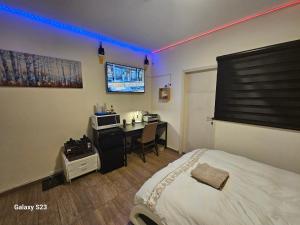 Habitación de hotel con cama, escritorio y TV. en Cool place in Ramat Gan en Ramat Gan