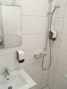 ein Bad mit einer Dusche, einem Waschbecken und einem Spiegel in der Unterkunft Aparthotel Sanni in Bremen