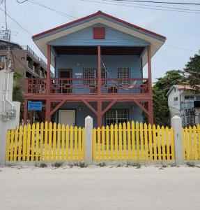 ein gelber Zaun vor einem Haus mit Balkon in der Unterkunft Villa Hermosa- 2 Bedroom Home in Caye Caulker