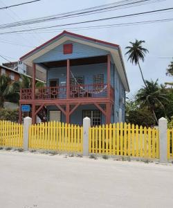 ein gelber Zaun vor einem Haus mit Balkon in der Unterkunft Villa Hermosa- 2 Bedroom Home in Caye Caulker