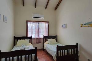 zwei Betten in einem Zimmer mit Fenster in der Unterkunft Villa Hermosa- 2 Bedroom Home in Caye Caulker