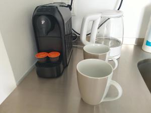 Aparthotel Sanni في بريمين: كوبين على منضدة بجانب آلة صنع القهوة