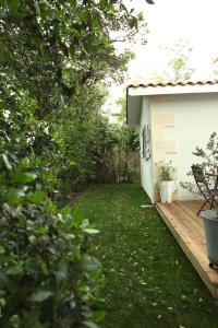 a yard with a wooden deck next to a house at Villa Petit Caprice - Piscine privée au calme dans jardin arboré in Lanton