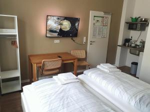 2 łóżka w pokoju z biurkiem i stołem w obiekcie Aparthotel Sanni w Bremie
