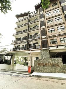 un gran edificio con un cartel delante en Cozy Pine Suites, en Baguio