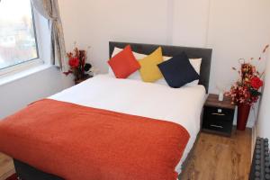 Un dormitorio con una cama con almohadas de colores y una ventana en RB, en Stockport