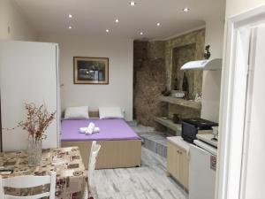 ペレカスにあるAgnes Roomsの紫色のベッドとテーブルが備わる客室です。