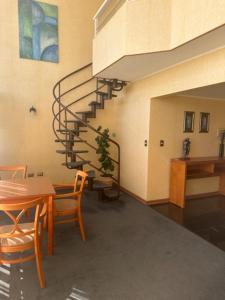 sala de estar con escalera, mesa y sillas en Hotel Florencia Suites & Apartments, en Antofagasta