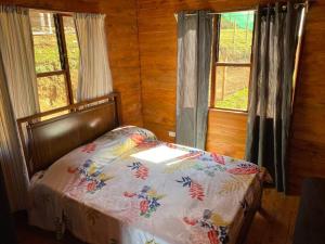 a bed in a room with two windows at Cabaña Princesa Roja - PERFECT view of the valley! in San Pablo
