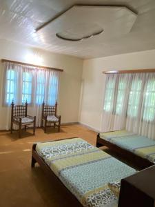 Pokój z 2 łóżkami, 2 krzesłami i oknami w obiekcie Shangrilla House Murree, Bhurban w mieście Murree