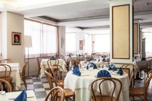 a dining room with tables and chairs with blue napkins at Hotel Los Angeles in Assisi