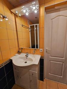 a bathroom with a sink and a mirror and a door at Jaukus butas Palangoje arti jūros in Palanga +4 photos