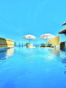 einen Pool mit blauem Wasser und Sonnenschirmen in der Unterkunft Lembongan Harmony Villas in Nusa Lembongan