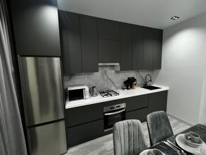 eine Küche mit schwarzen Schränken und einem Kühlschrank aus Edelstahl in der Unterkunft Lux в ЖК K7-Family рядом аэропорт in Atyrau