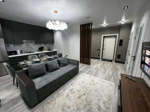 ein Wohnzimmer mit einem grauen Sofa und einem Tisch in der Unterkunft Lux в ЖК K7-Family рядом аэропорт in Atyrau