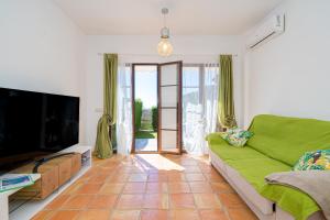 sala de estar con sofá verde y TV en Bahia Vista - Chalet adosado con vista al mar en Finestrat