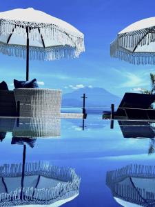 a pool with an umbrella and a cross in the background at Lembongan Harmony Villas in Nusa Lembongan