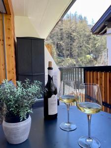 a bottle of wine sitting on a table with two glasses at Studio Wolli - Stylish & Central - steps to Matterhorn gondola in Zermatt