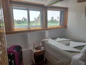 Dahabiya Nile Cruise في الأقصر: غرفة صغيرة بها سرير ونوافذ