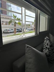 eine Couch mit einem Kissen vor einem Fenster in der Unterkunft Wood-Finish Home Pool Premium Bedding Self-Check in 7 Min from Marina in Agadir