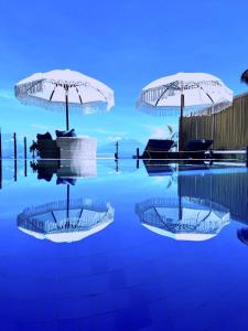 a swimming pool with two umbrellas and some chairs at Lembongan Harmony Villas in Nusa Lembongan