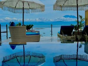 uma piscina com cadeiras e guarda-sóis e o oceano em Lembongan Harmony Villas em Nusa Lembongan