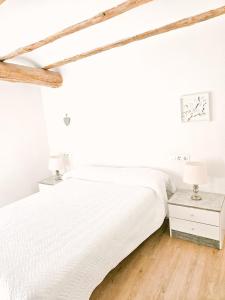 a white bedroom with a bed and a nightstand at Casa del Arquillo in Teruel