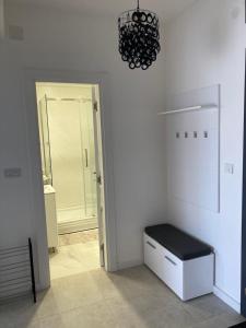 a room with a white wall with a bench and a chandelier at Sears Residence Apartments in Tivat