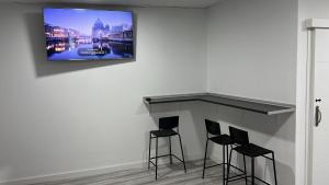 a room with three bar stools and a tv on a wall at O Albergue de Fene in Fene