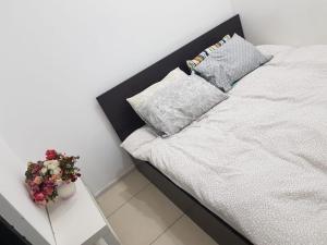 een wit bed met 2 kussens en een tafel met bloemen bij Apartament JOSEFIN in Timişoara
