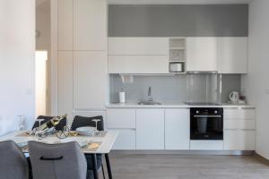 a kitchen with white cabinets and a table with chairs at Apartmani Jakić 2 in Hvar