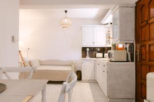 a kitchen with white cabinets and a table and chairs at Naxian Harmony Town Suites in Naxos Chora