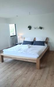 duże łóżko w sypialni z drewnianą podłogą w obiekcie Helle freundliche Wohnung am Stadtpark w mieście Bobingen