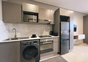 eine Küche mit einer Waschmaschine, einer Spüle und einem Kühlschrank in der Unterkunft Top-Floor Urban Oasis located in the heart of Sandton City Center in Johannesburg
