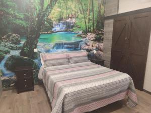 1 dormitorio con 1 cama con un mural de cascada en Hostal El Bosque Encantado Toledo, en Toledo