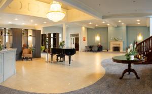 een grote lobby met een piano en een woonkamer bij Great National Hotel Ballina in Ballina