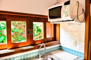 uma cozinha com um lavatório e um micro-ondas em Suítes Forte Rocha em Ilhabela