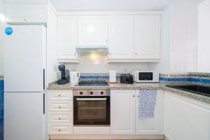 a kitchen with white cabinets and a white refrigerator at Bahia Vista - Chalet adosado con vista al mar in Finestrat