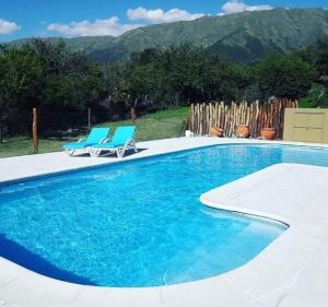 a swimming pool with two blue chairs next to asenalsenalsenalsenal at San Luis Aparts in Carpintería