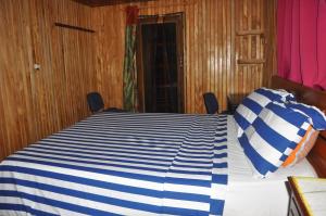 ein Schlafzimmer mit einem Bett mit einer blau-weißen gestreiften Bettdecke in der Unterkunft Appartement Chalet type f3 in Kribi