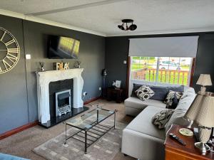 sala de estar con sofá y chimenea en Sunshine Lodge Haven Lakeland, en Flookburgh