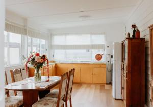 eine Küche mit einem Tisch mit einer Vase mit Blumen darauf in der Unterkunft Falmouth Cottage - Dog Friendly Beachside Getaway 2,5 Acres in Falmouth