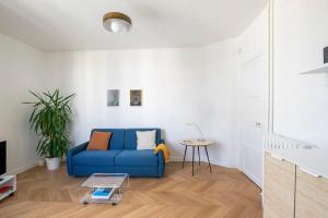 een woonkamer met een blauwe bank en een tafel bij 2p 36m2 Moderne et au Calme à 10 min de Paris et la Défense in La Garenne-Colombes