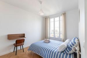 een slaapkamer met een bed, een stoel en een raam bij 2p 36m2 Moderne et au Calme à 10 min de Paris et la Défense in La Garenne-Colombes