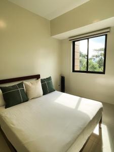 1 dormitorio con 1 cama blanca grande y ventana en Cozy Pine Suites, en Baguio