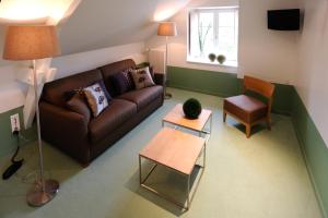 a living room with a brown couch and a chair at La Ferme des Mares, Demeures & Châteaux in Saint-Germain-sur-Ay