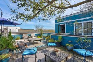 eine Terrasse mit Stühlen und Tischen und ein blaues Haus in der Unterkunft Elegant Sunlit Home with Private Rooftop Oasis in Charleston