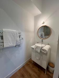 uma casa de banho branca com um lavatório e um espelho em Maison calme du bassin em Lanton